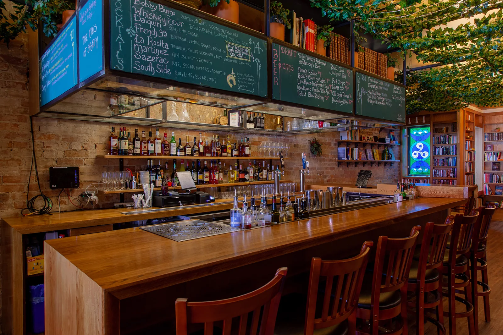 Wooden bar, stools and hanging greenery at Danu Social House
