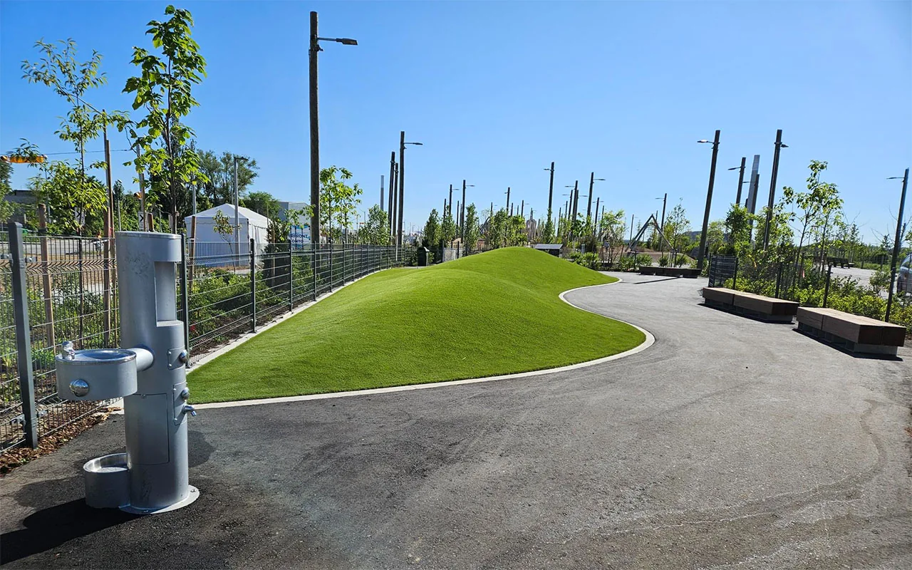 Dog water fountain, paved path, turf and fencing at Biidaasige Park
