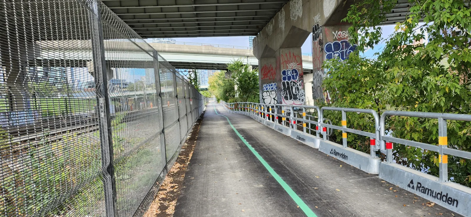 Paved Lower Don Trail with railway fencing near the Queen Street bridge