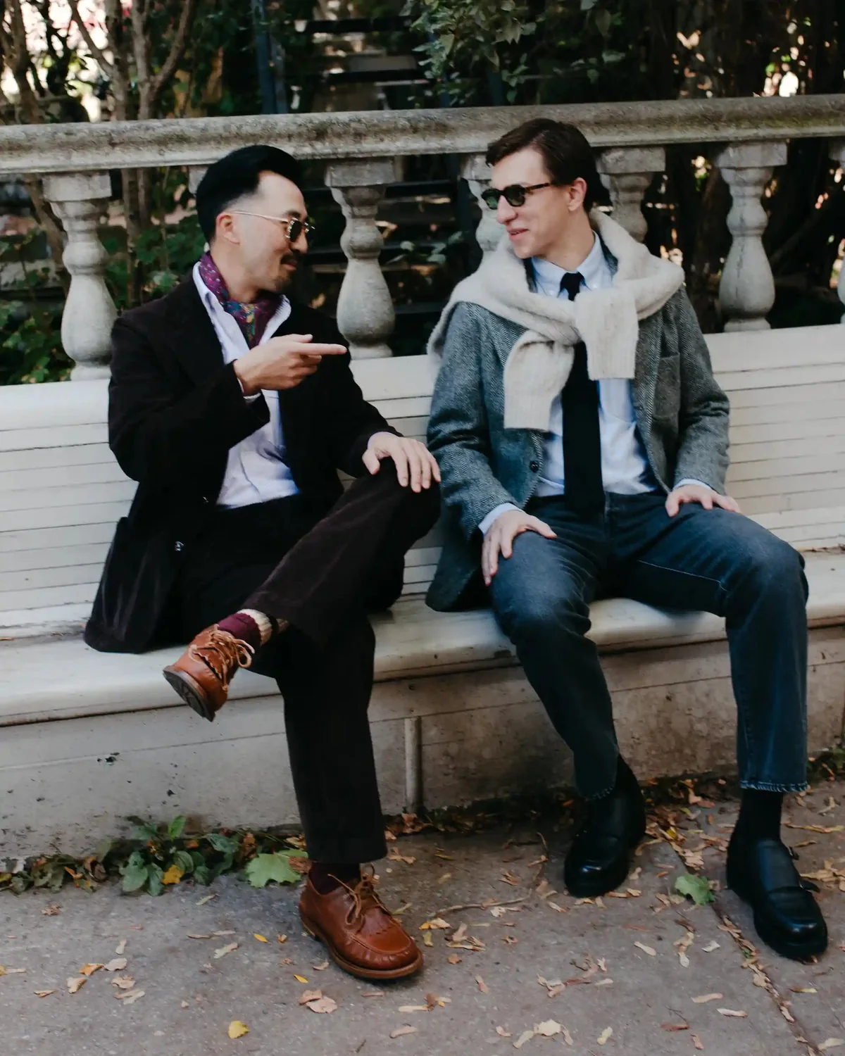 Two men seated outdoors wearing jackets and trousers