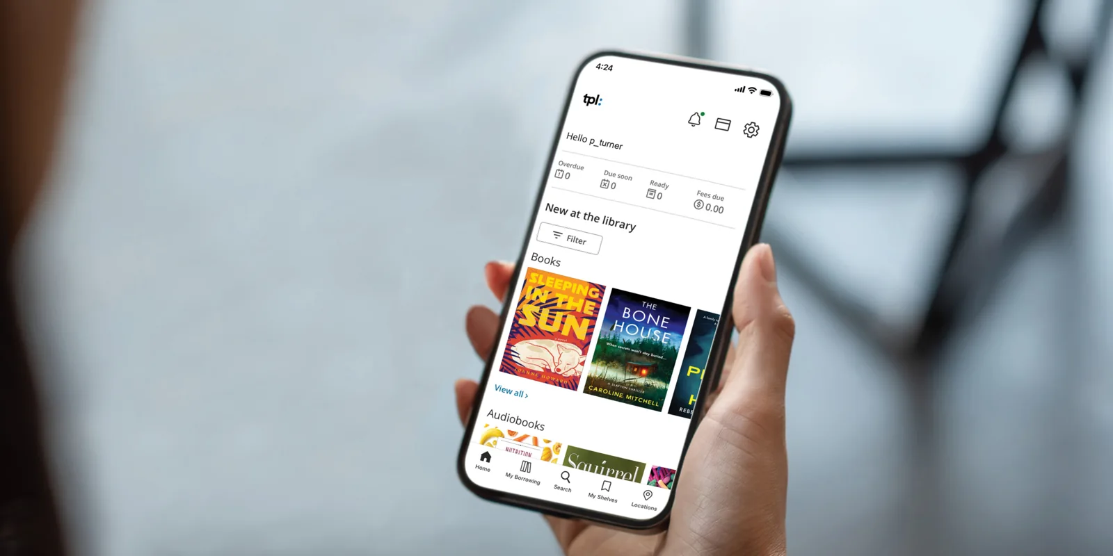 A hand holding a phone with Toronto Public Library’s app open