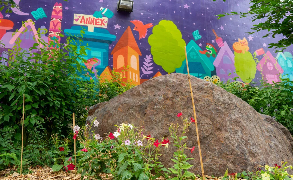 Flowers, a large stone and Daniela Rocha’s colourful mural at the Major Street parkette