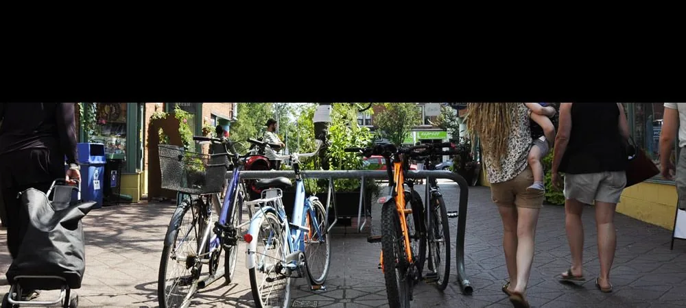 Bicycles and pedestrians beside shopfront patios on the Danforth