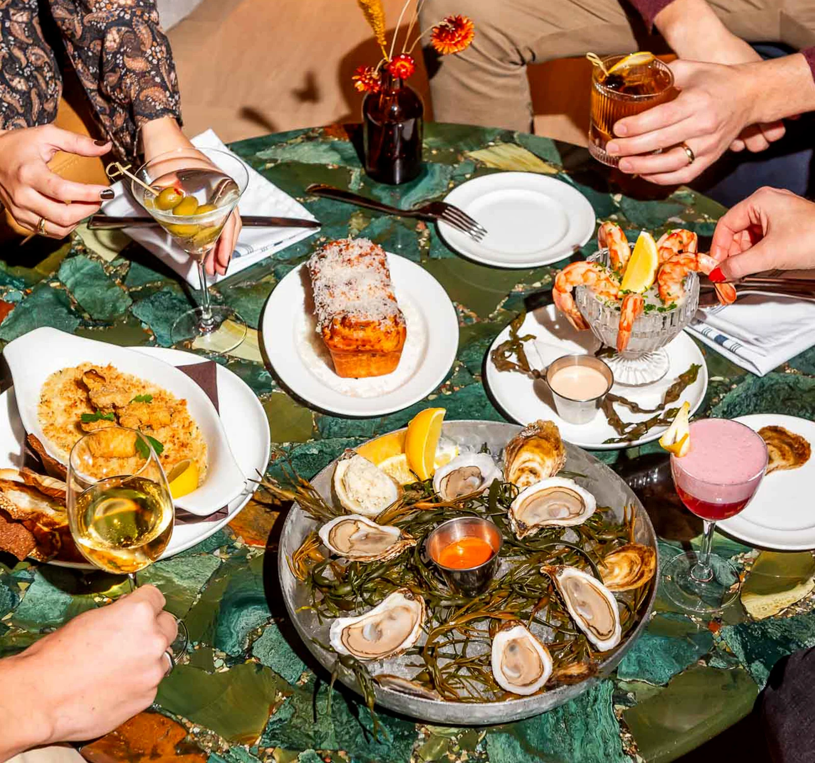 Several food dishes and drinks shared around a restaurant table