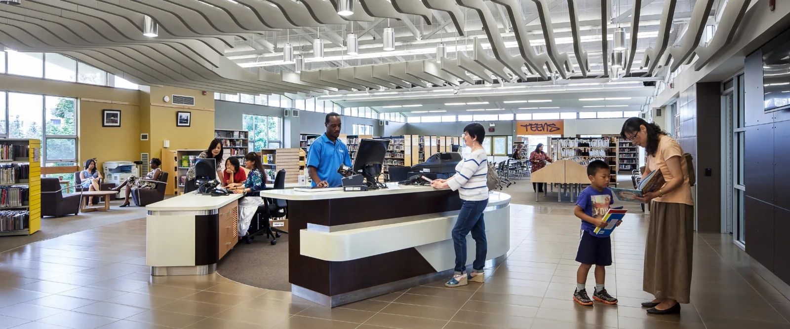Families and other visitors looking at books near a library desk