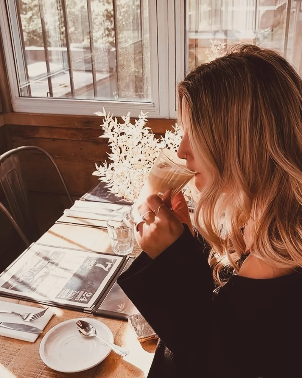 A woman reading with coffee in a photo shared by 7 West Café